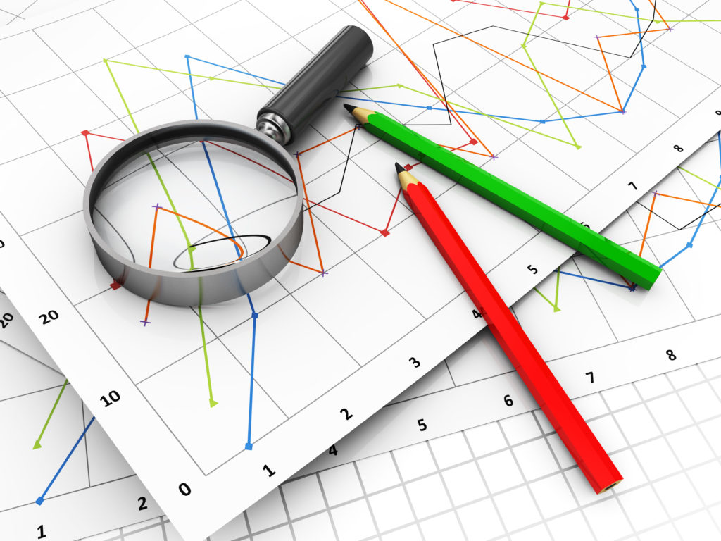 Image of focussing on the aspects of a line chart with a magnifying glass and pencils.